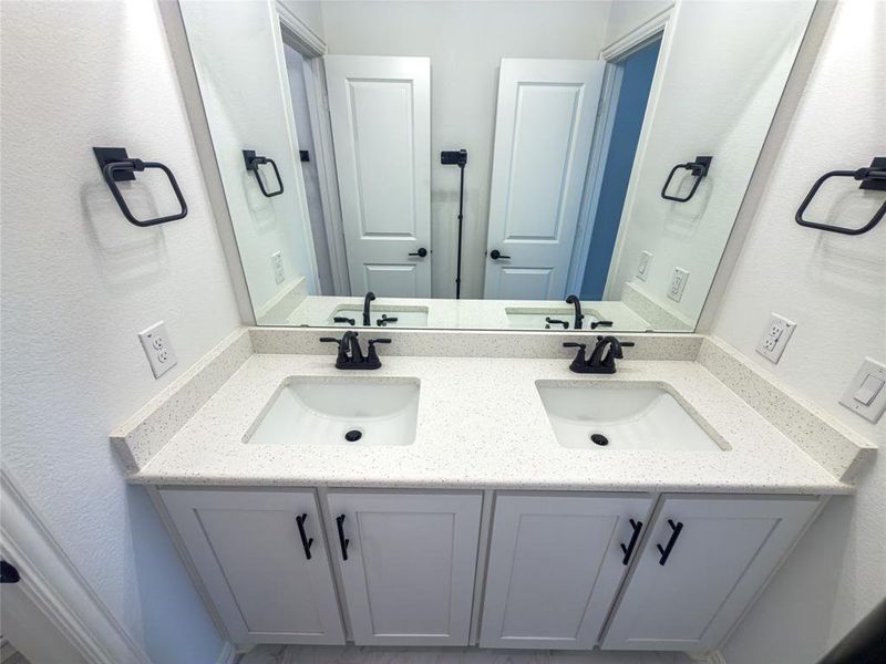 Bathroom with double vanity and a textured wall