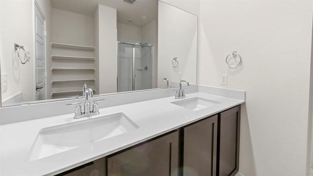 Full bathroom featuring double vanity and a stall shower
