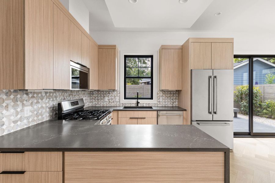 Kitchen featuring light brown cabinets, stainless steel appliances, dark stone countertops, decorative backsplash, and recessed lighting Kitchen featuring light brown cabinets, stainless steel appliances, dark stone countertops, decorative backsplash, and recessed lighting