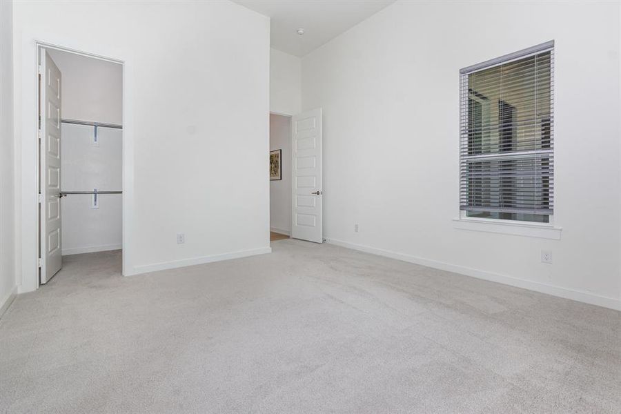 Unfurnished bedroom featuring a walk in closet and light colored carpet Unfurnished bedroom featuring a walk in closet and light colored carpet