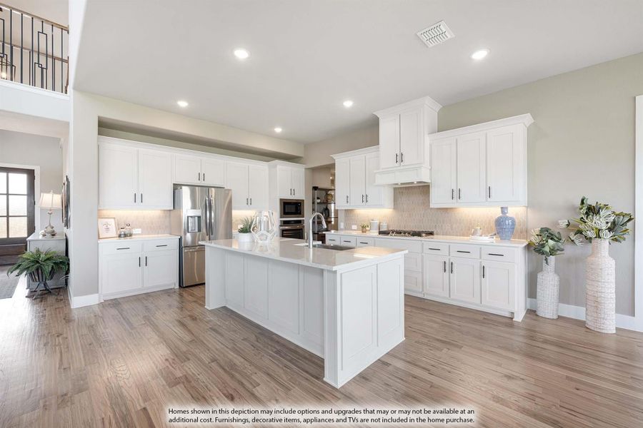 Open kitchen with white cabinets, large center island, stainless appliances, and light wood floors