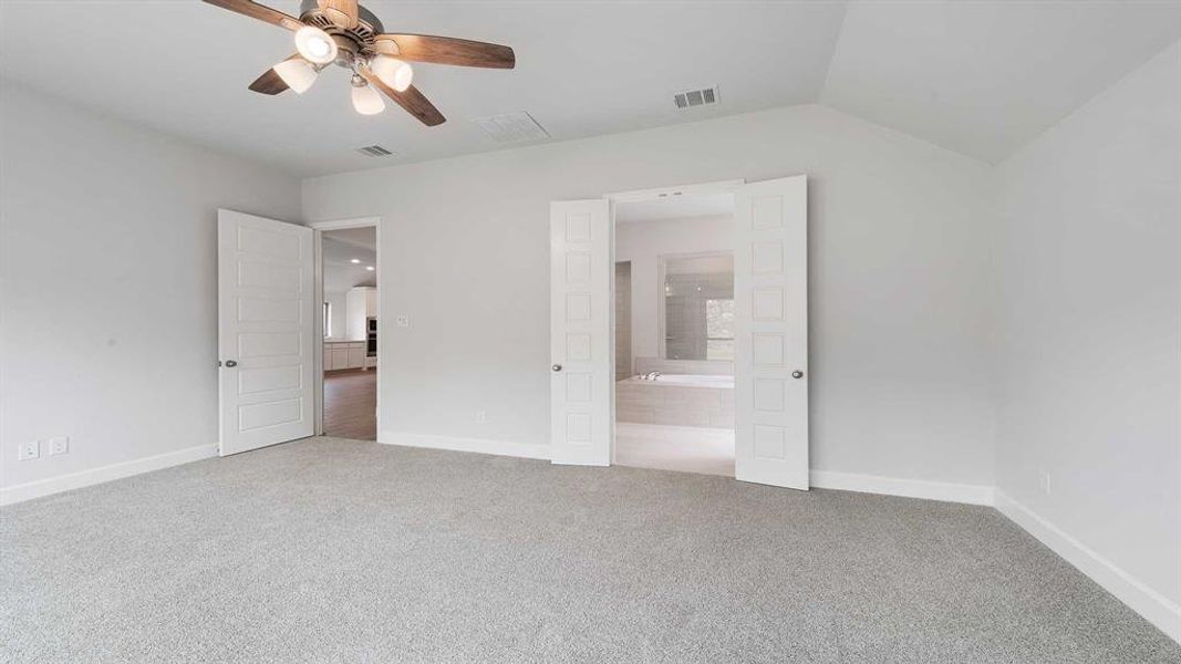 Unfurnished bedroom with lofted ceiling, ceiling fan, carpet floors, and ensuite bath