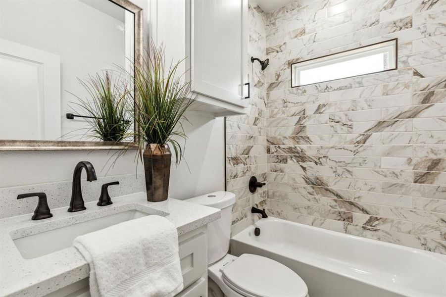 Full bathroom featuring vanity, tiled shower / bath, and toilet