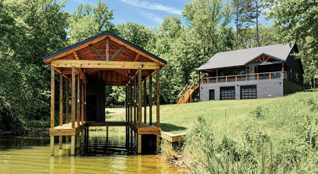 Waterfront property featuring a custom boat dock with a gabled roof, natural wood construction, and integrated lighting
