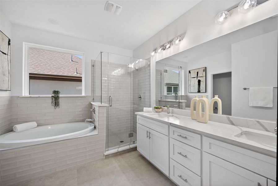Full bath with double vanity, a bath, a stall shower, and plenty of natural light