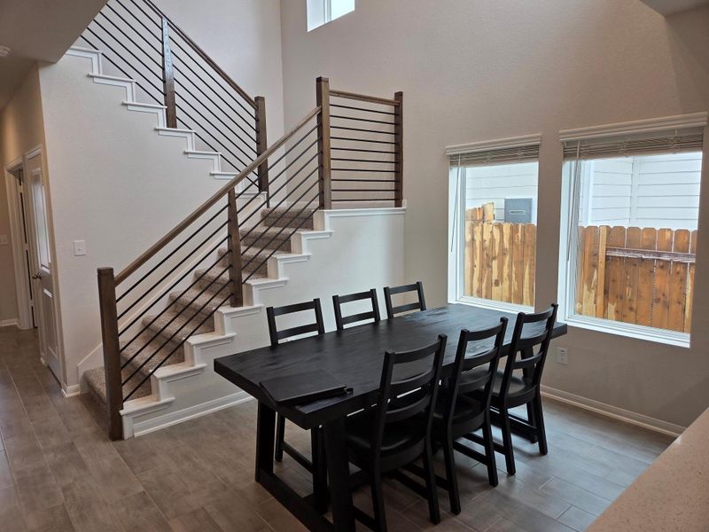 Two-story foyer with wood-finish flooring, contemporary horizontal stair railing, high ceilings, and abundant natural light from multiple windows