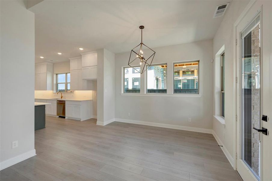 Unfurnished dining area with a chandelier and light wood-style floors