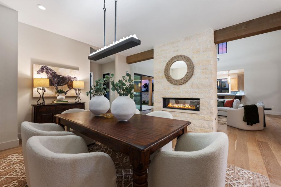 Beautiful formal dining room with custom chandelier and double-sided rock fireplace.