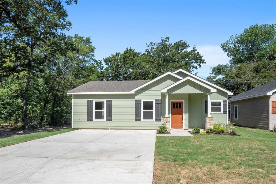 Sage green exterior with white trim, a covered porch, and a bright orange entry door Sage green exterior with white trim, a covered porch, and a bright orange entry door