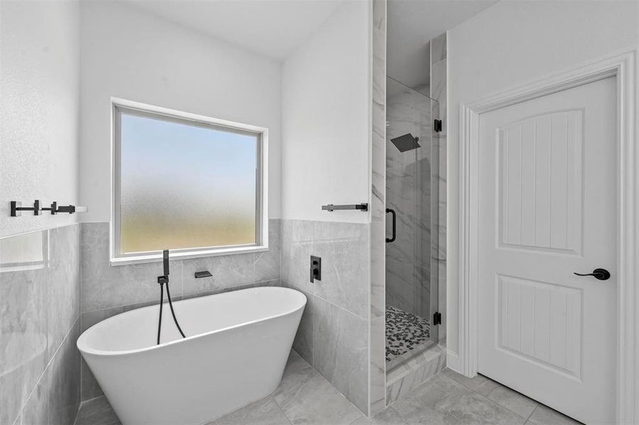 Bathroom with tile walls, tile patterned floors, and shower with separate bathtub