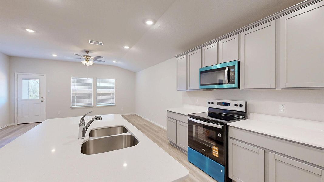 A well-appointed kitchen features an island with a double sink and stainless steel appliances.