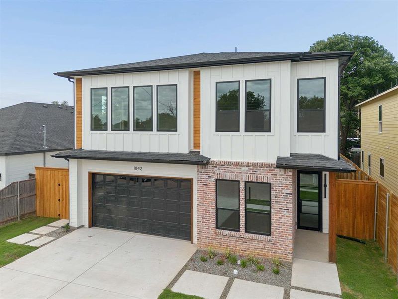 Contemporary two-story exterior featuring a mix of white vertical siding, light brick, and wood-finish accents Contemporary two-story exterior featuring a mix of white vertical siding, light brick, and wood-finish accents