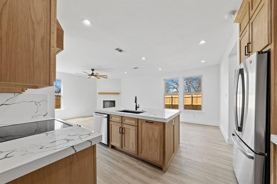 Kitchen with a sink, visible vents, open floor plan, appliances with stainless steel finishes, and an island with sink