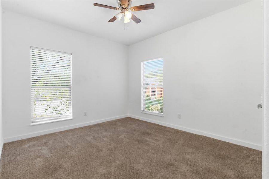 Carpeted empty room with baseboards and a ceiling fan Carpeted empty room with baseboards and a ceiling fan