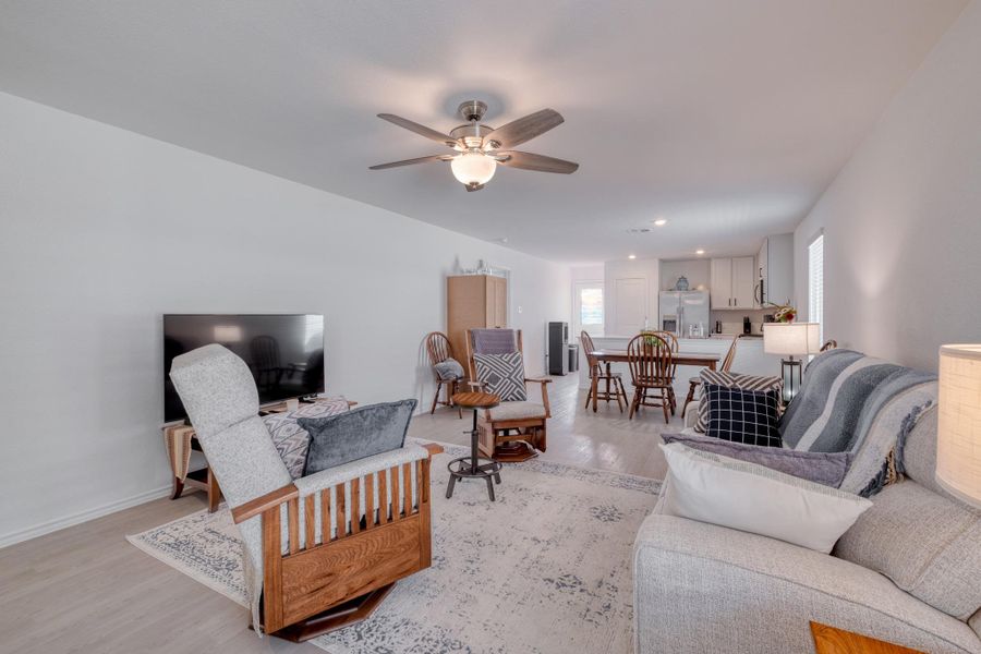 The open concept living area features light-colored flooring, a ceiling fan with integrated lighting, and a neutral color palette