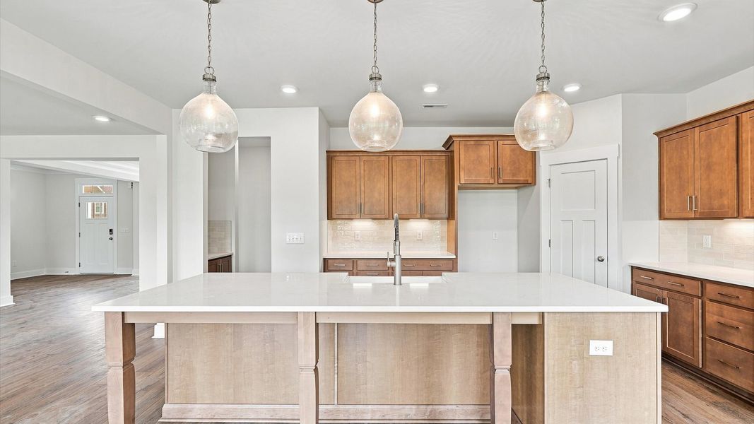 Highly skilled kitchen design includes a 10-foot island, quartz countertops, and stylish pendant fixtures