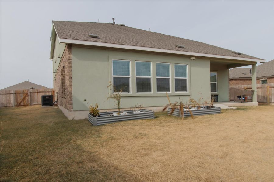 Spacious backyard with fencing, a flourishing garden, expansive covered patio, and attractive stucco exterior.