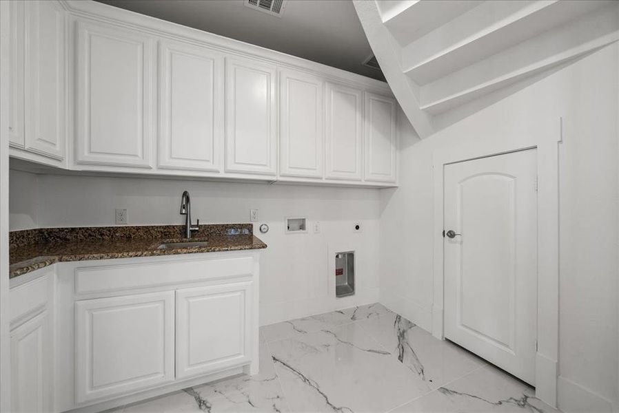 Utility room with hookup for a washer/dryer, light marble finish flooring, and ample cabinet space Utility room with hookup for a washer/dryer, light marble finish flooring, and ample cabinet space