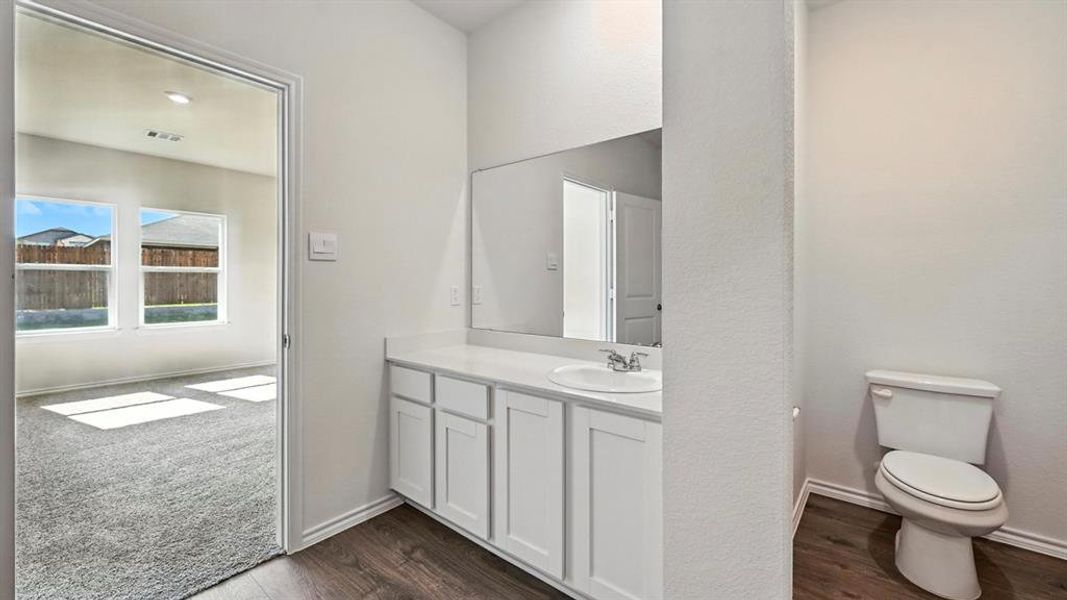 Bathroom vanity area featuring white cabinetry, a single basin sink, and a large wall-mounted mirror