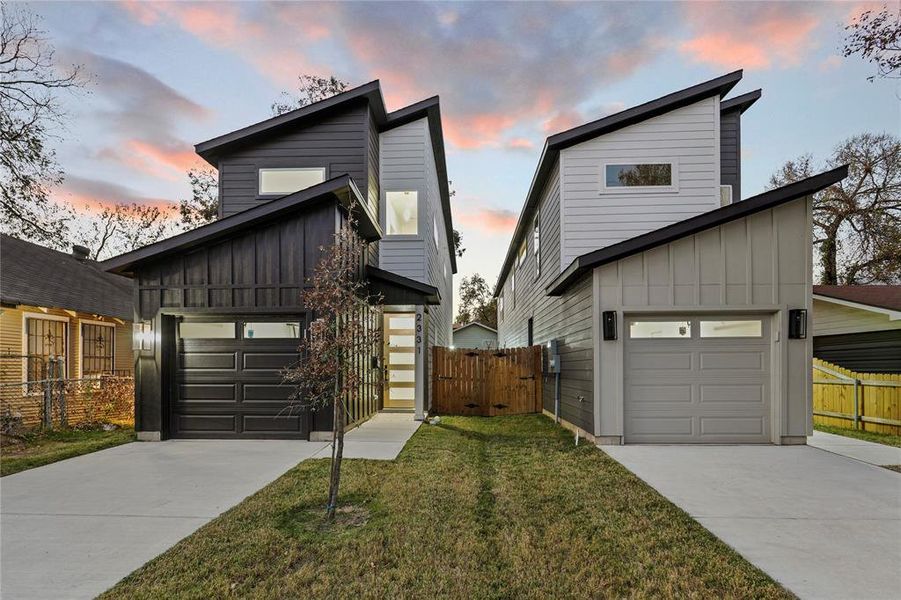 Contemporary house featuring board and batten siding, a garage, concrete driveway, and a gate