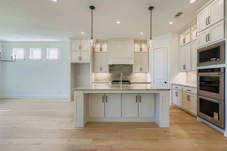Kitchen with appliances with stainless steel finishes, recessed lighting, light wood-style floors, a kitchen island with sink, and pendant lighting