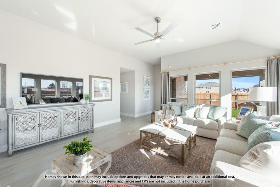 Bright living room with vaulted ceiling, ceiling fan, light wood floors, and large windows Bright living room with vaulted ceiling, ceiling fan, light wood floors, and large windows