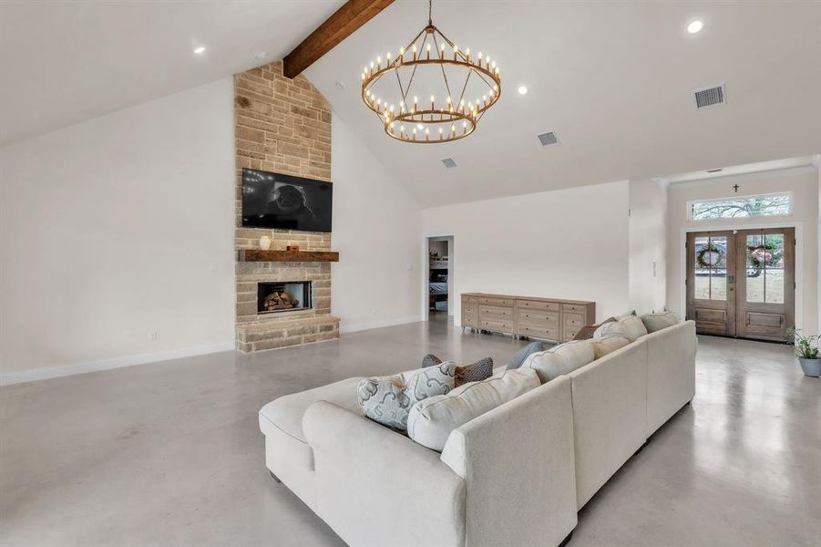Living area with french doors, finished concrete flooring, a fireplace, and a chandelier Living area with french doors, finished concrete flooring, a fireplace, and a chandelier