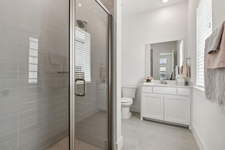 Guest Bathroom featuring toilet, tile patterned floors, a shower with door, and vanity