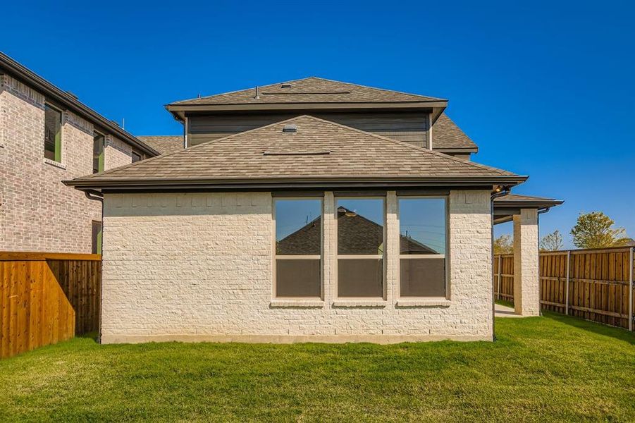 Back of house featuring a fenced backyard, roof with shingles, and a patio area