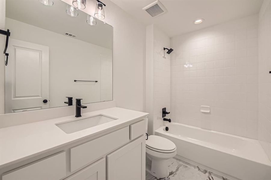Full bath with vanity, toilet, marble look tiles, shower / bath combination, and recessed lighting Full bath with vanity, toilet, marble look tiles, shower / bath combination, and recessed lighting