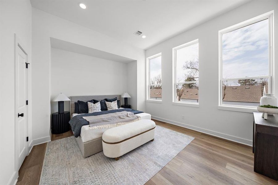 Spacious primary bedroom filled with natural light from large windows, offering a serene retreat with modern elegance.