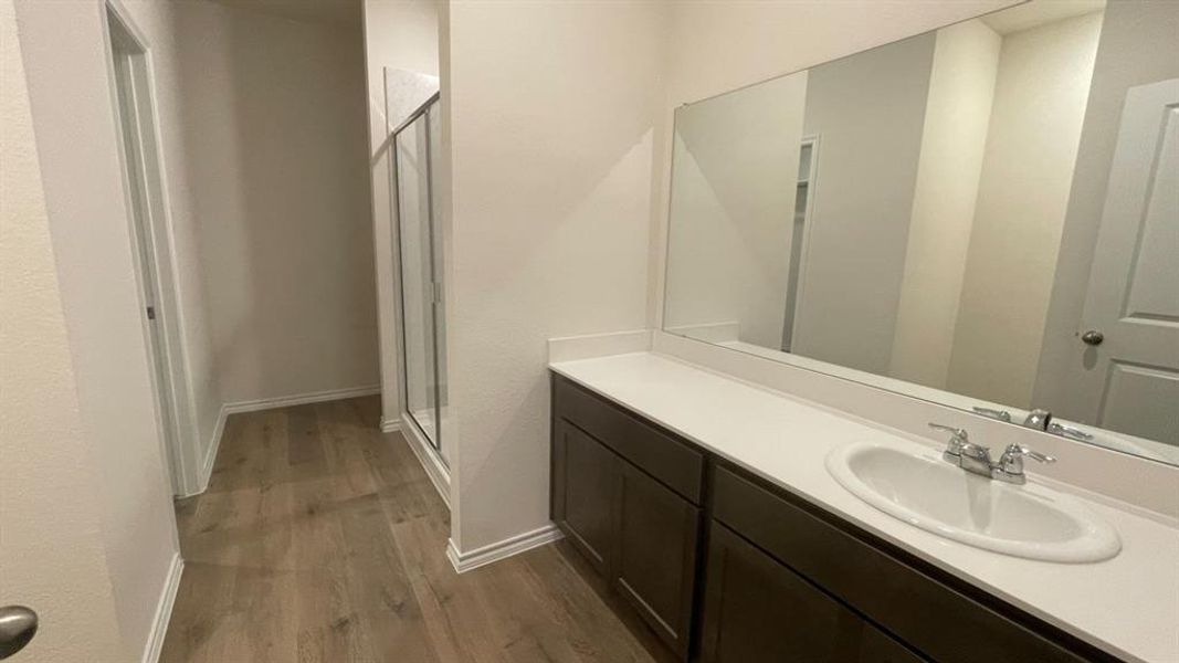 Bathroom vanity featuring a single-bowl sink, chrome faucet, white countertop, and dark wood-finish cabinetry Bathroom vanity featuring a single-bowl sink, chrome faucet, white countertop, and dark wood-finish cabinetry
