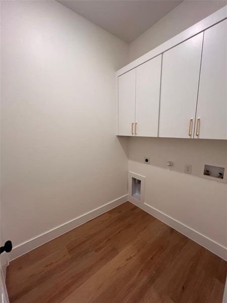 Laundry area with gas dryer hookup, hookup for an electric dryer, washer hookup, dark hardwood / wood-style flooring, and cabinets