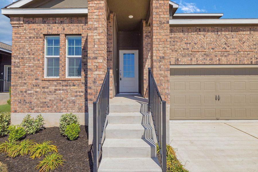 Doorway to property with brick siding, driveway, and a garage