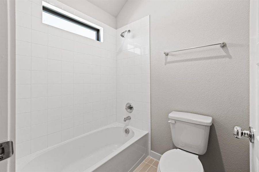 Bathroom with toilet, tile floors, and tiled shower / bath combo
