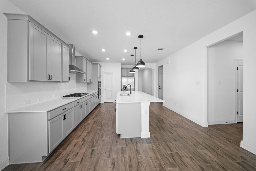 Kitchen with a center island with sink, recessed lighting, light stone countertops, hanging light fixtures, and dark wood-type flooring Kitchen with a center island with sink, recessed lighting, light stone countertops, hanging light fixtures, and dark wood-type flooring