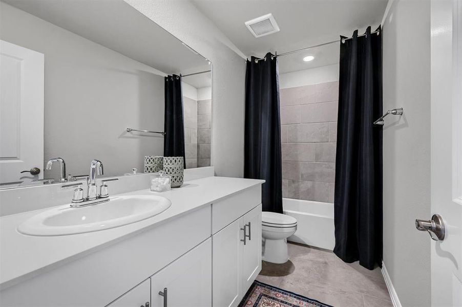 Full bathroom featuring toilet, tile patterned floors, vanity, and shower / tub combo with curtain