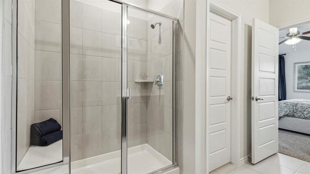 The bathroom features a glass-enclosed shower with a tiled interior and a built-in shelf