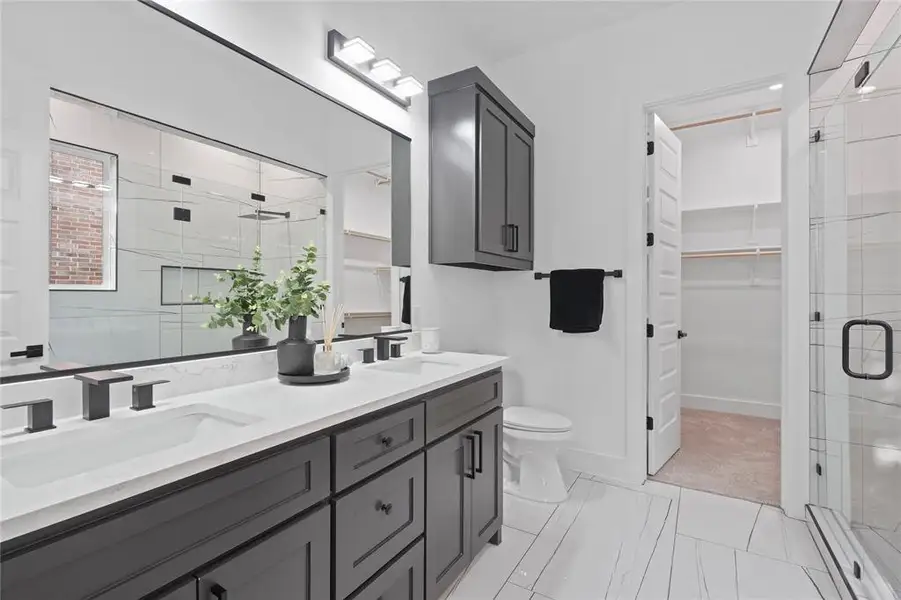 Bathroom featuring double vanity, a stall shower, and a walk in closet