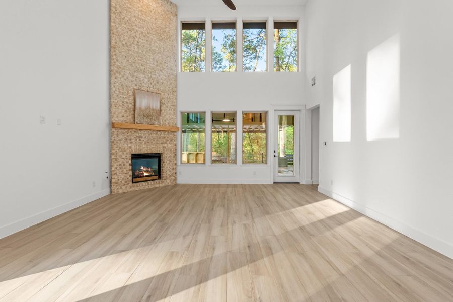 This spacious living room features high ceilings, large windows for natural light, a fireplace with a stone surround, and light wood flooring. The room offers a bright, airy feel with views of the outdoors. This spacious living room features high ceilings, large windows for natural light, a fireplace with a stone surround, and light wood flooring. The room offers a bright, airy feel with views of the outdoors.