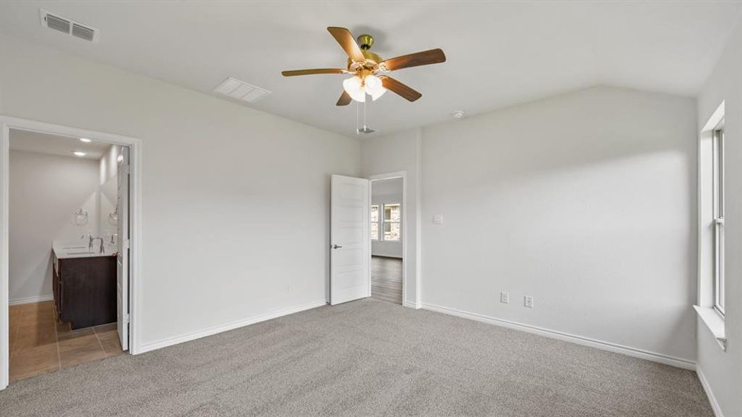 Carpeted room with vaulted ceiling and a ceiling fan with light kit Carpeted room with vaulted ceiling and a ceiling fan with light kit