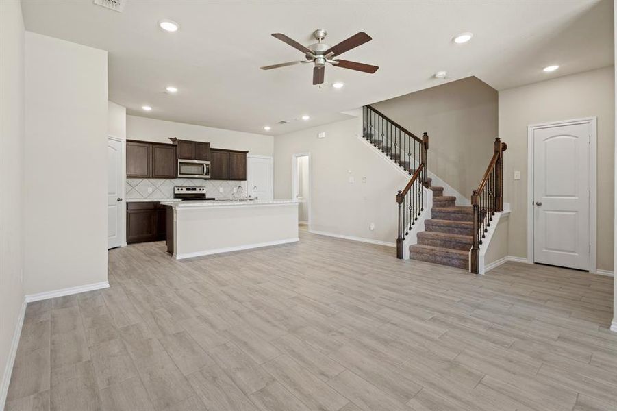 Unfurnished living room with stairway, light wood-style floors, recessed lighting, and a ceiling fan Unfurnished living room with stairway, light wood-style floors, recessed lighting, and a ceiling fan