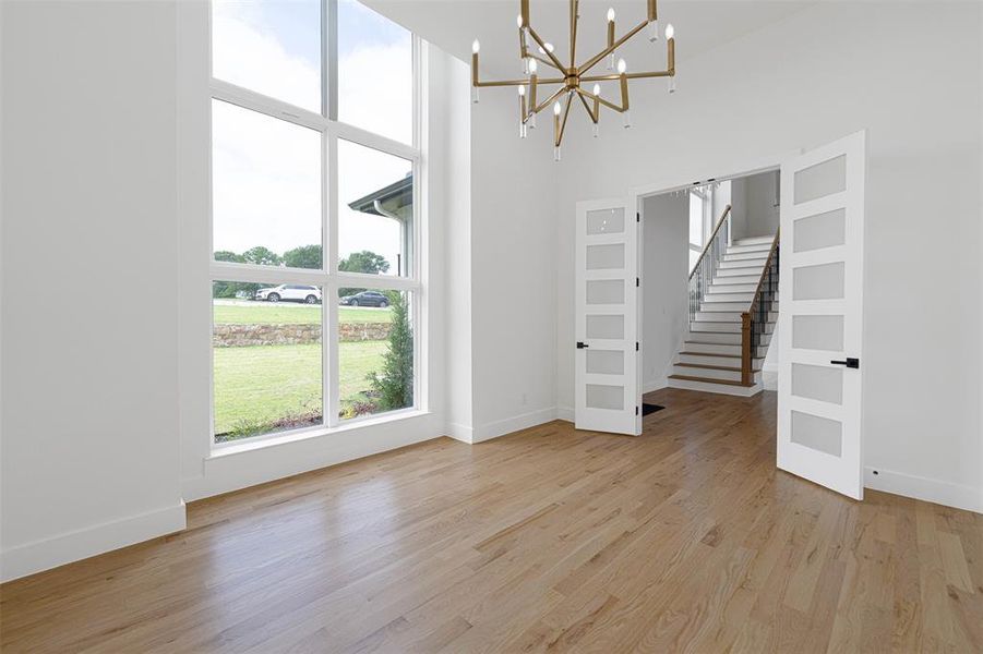 Study featuring light wood finished floors, a high ceiling, a chandelier, and baseboards Study featuring light wood finished floors, a high ceiling, a chandelier, and baseboards