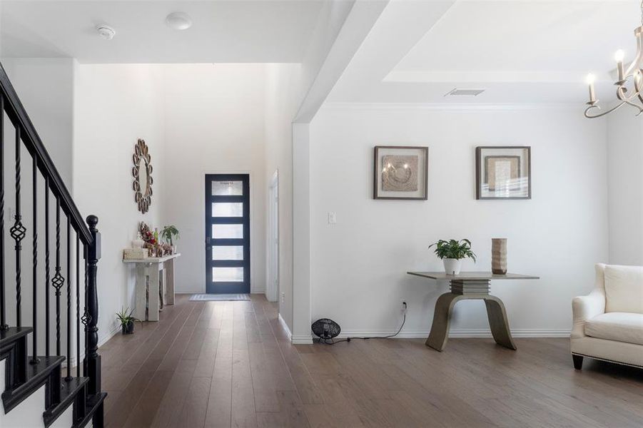 Entrance foyer with dark wood-type flooring, stairs, a chandelier, and ornamental molding