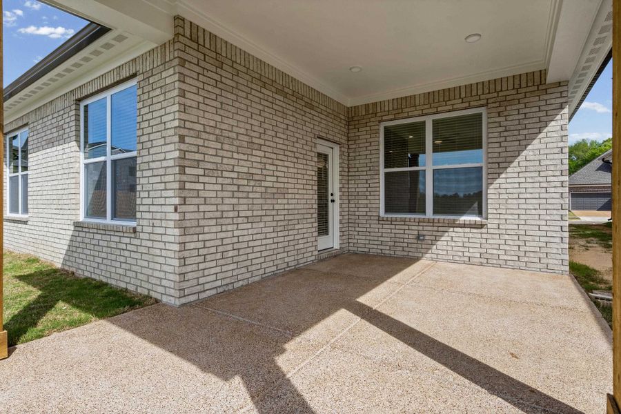 View of exterior entry with a patio and brick siding