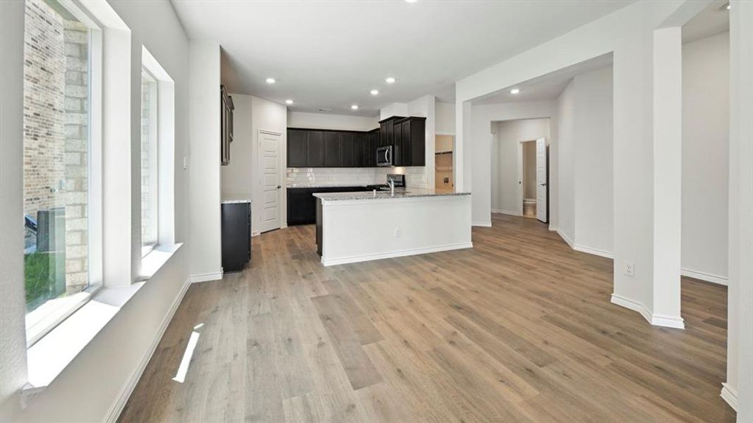 Kitchen featuring open floor plan, tasteful backsplash, recessed lighting, dark cabinetry, and light wood-style flooring