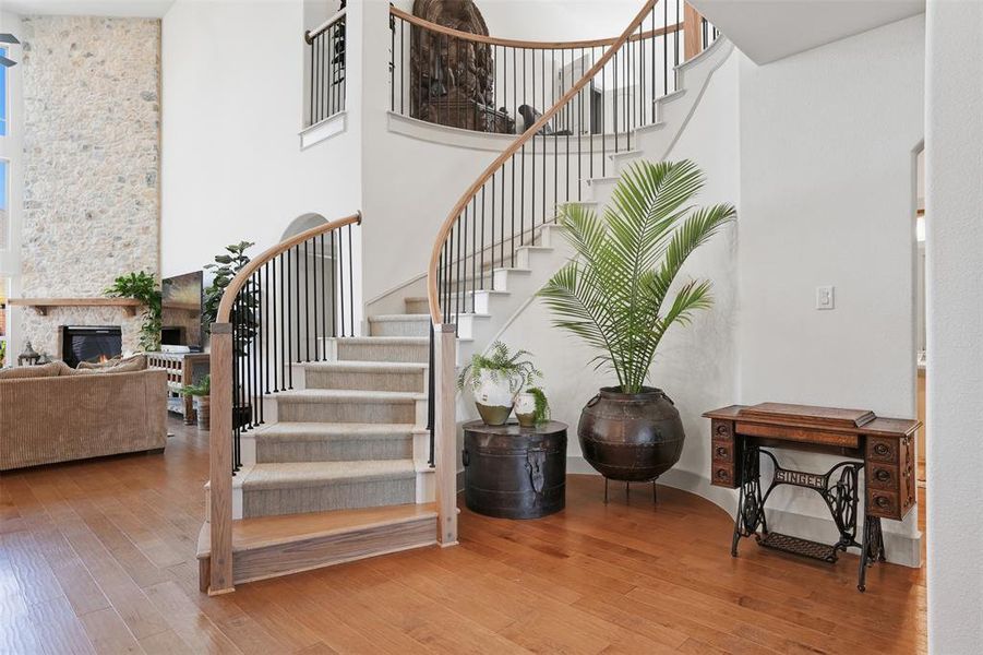 Stairway with hardwood / wood-style floors, a fireplace, and a towering ceiling Stairway with hardwood / wood-style floors, a fireplace, and a towering ceiling
