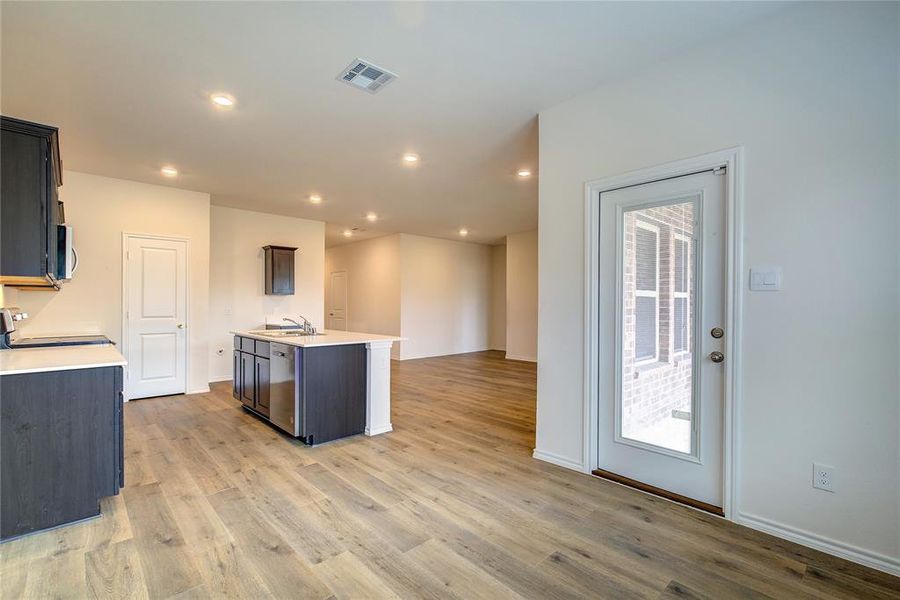 Kitchen with light wood-style floors, appliances with stainless steel finishes, open floor plan, light stone counters, and recessed lighting