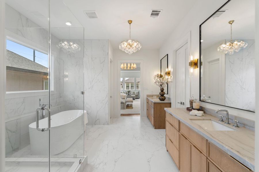The spa-inspired primary bath features dual vanities with custom cabinetry, quartz countertops, and designer lighting, creating a refined and functional space.