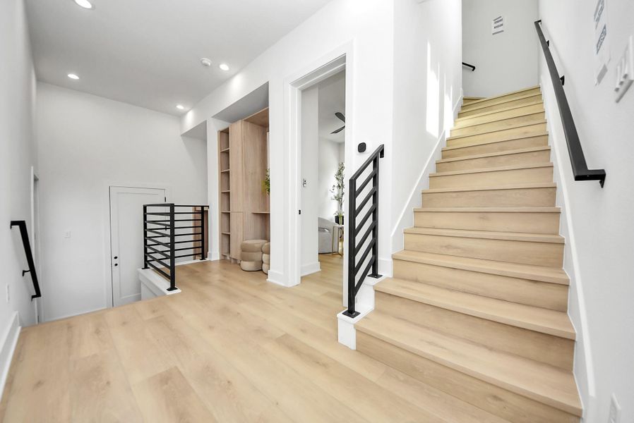 Open stair landing with sleek black railings and custom built-in storage.
